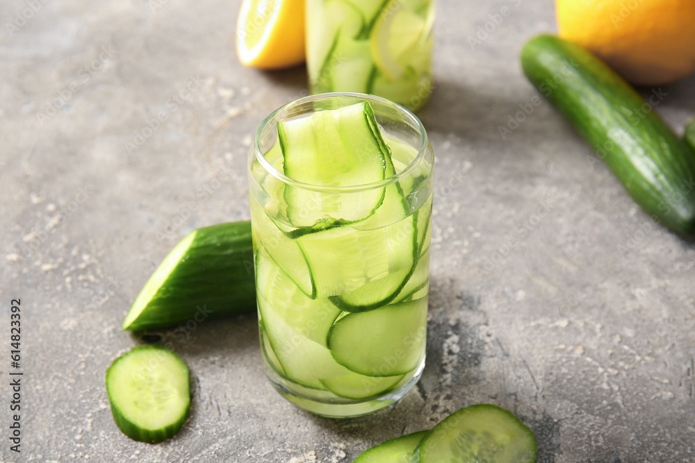 Glass of infused water with cucumber slices on grey background