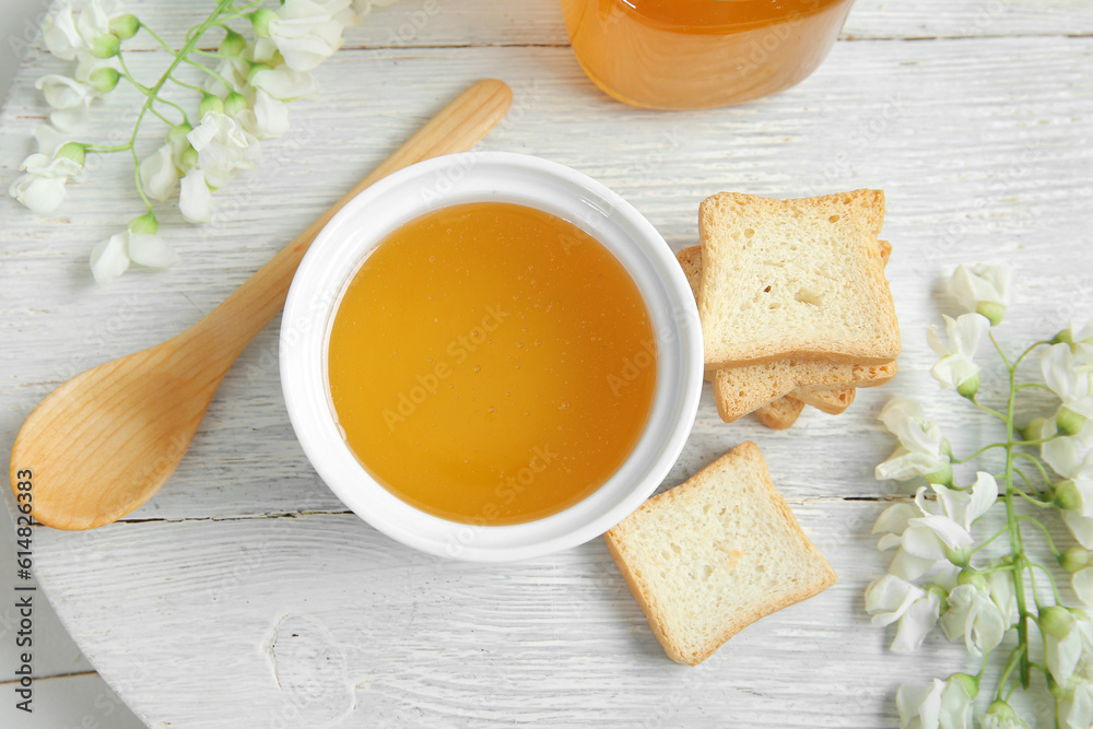 Composition with sweet honey, acacia flowers and crackers on light wooden background, closeup