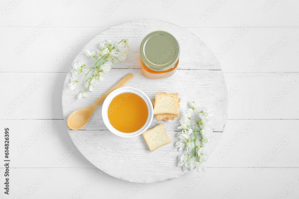 Composition with sweet honey, acacia flowers and crackers on light wooden background