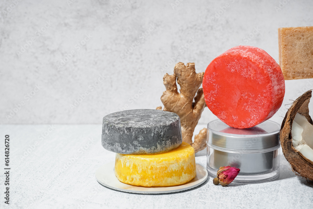 Different handmade solid shampoo, fruits and cream on light background, closeup