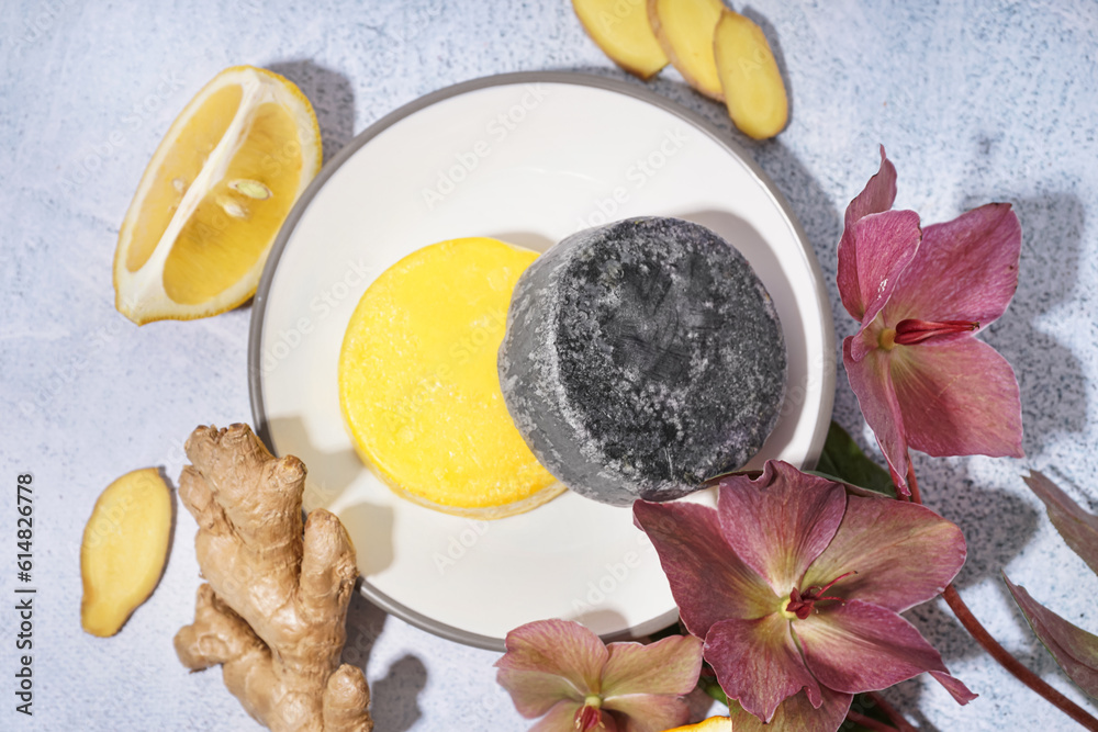 Different handmade solid shampoo, orchid flowers, lemon and ginger on light background