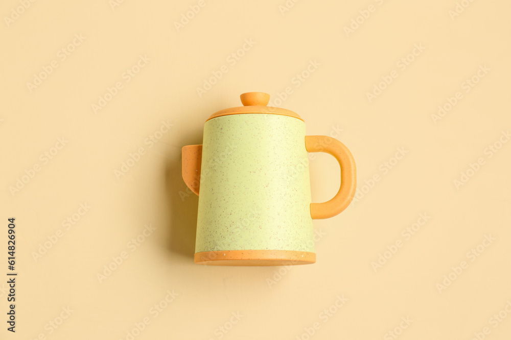 Yellow teapot for baby on pale orange background