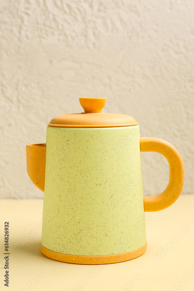 Yellow teapot for baby on pale orange table