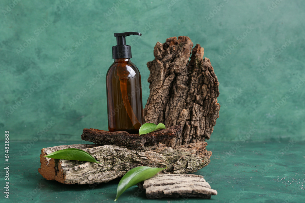 Composition with bottle of cosmetic product, tree bark and plant leaves on color background