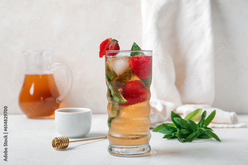 Glass of ice tea with strawberry and mint on white background