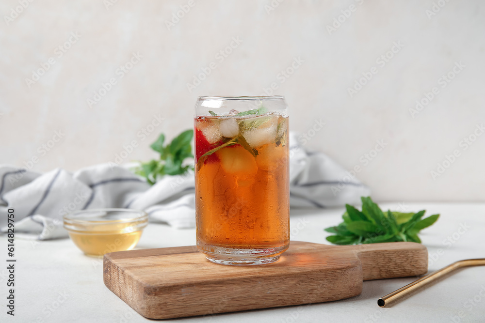 Glass of ice tea with strawberry and mint on white background