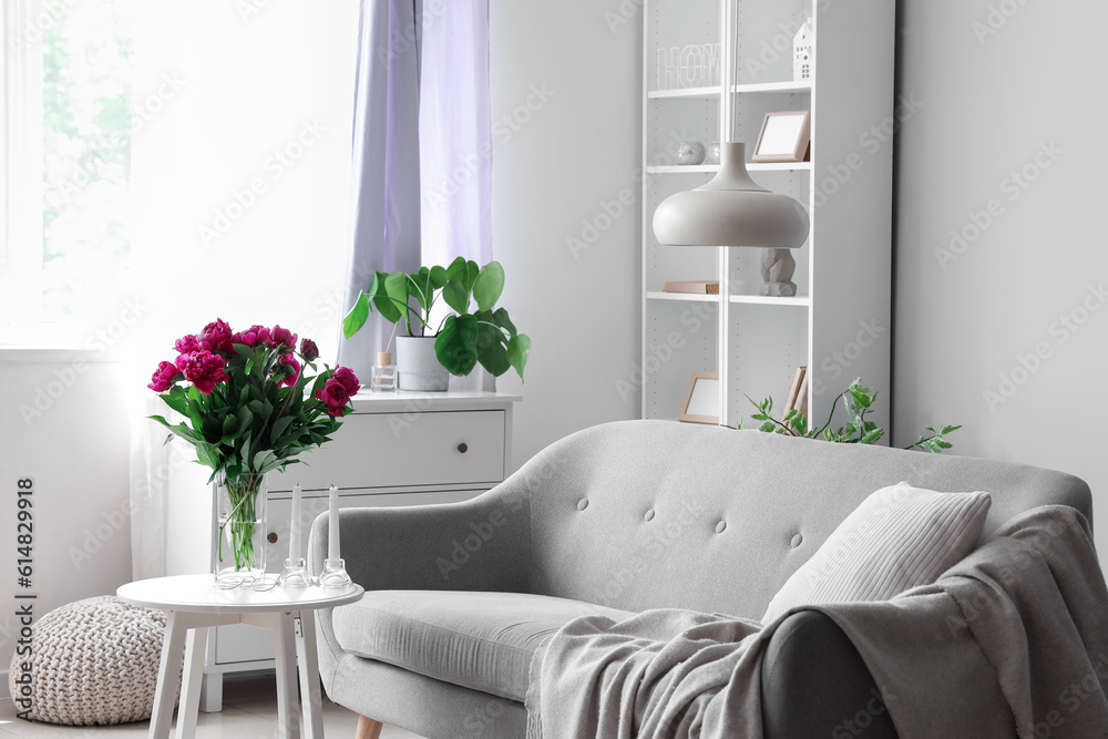 Vase with red peonies and candles on coffee table in living room