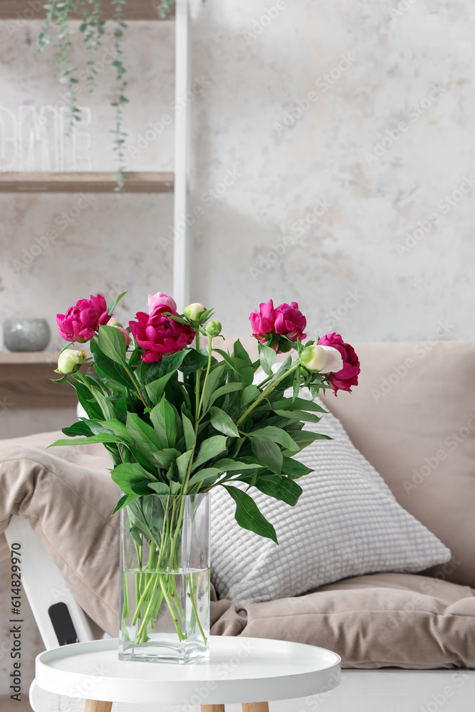 Vase with red peonies, couch and shelving unit in living room