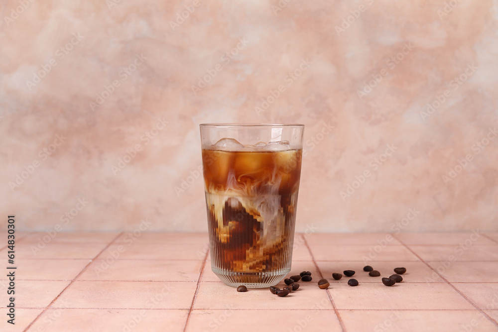 Glass of tasty ice coffee with milk on table