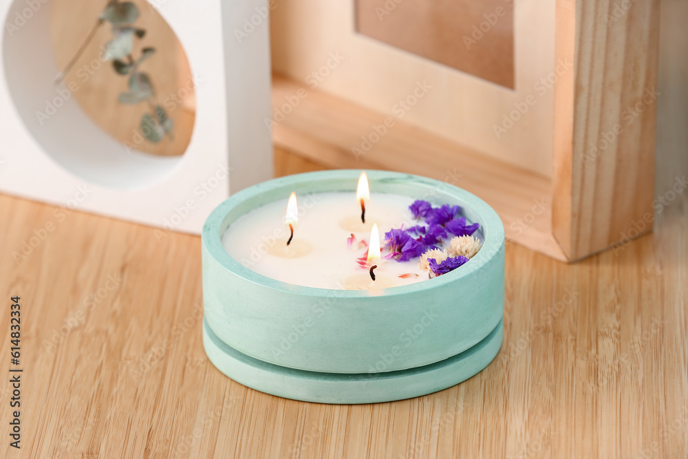 Holder with burning candle and decor on table in room, closeup