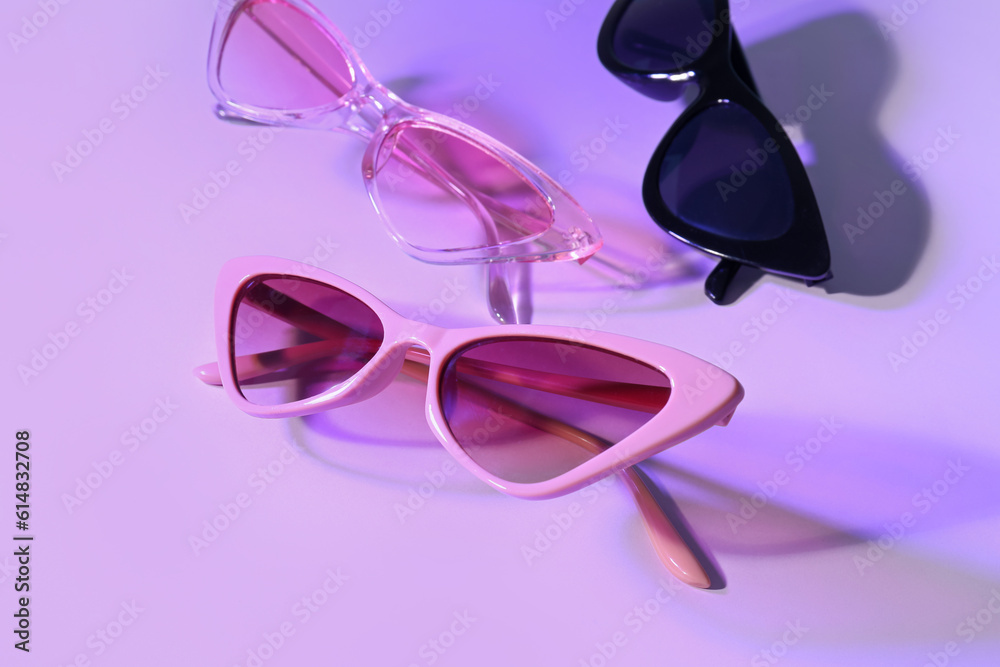 Different stylish sunglasses on lilac background