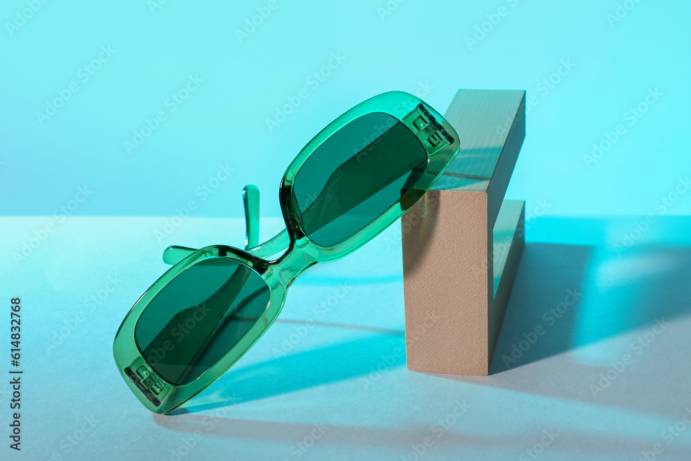 Podium with stylish sunglasses on blue background