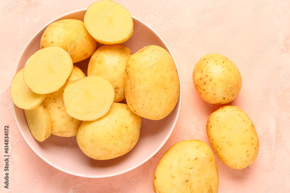 Bowl with raw baby potatoes on pink background