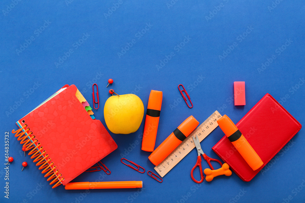 Fresh apple with different stationery on blue background