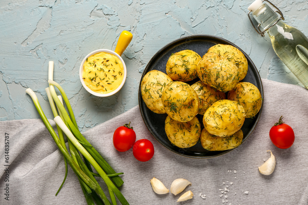 Plate of boiled baby potatoes with dill and sauce on blue background