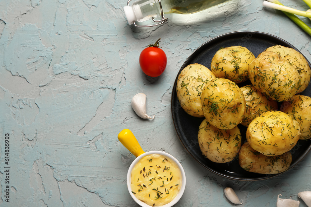 Plate of boiled baby potatoes with dill and sauce on blue background