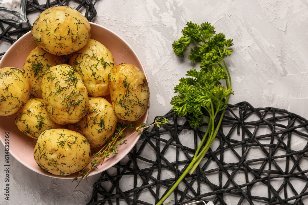 Bowl of boiled baby potatoes with dill and parsley on grey background