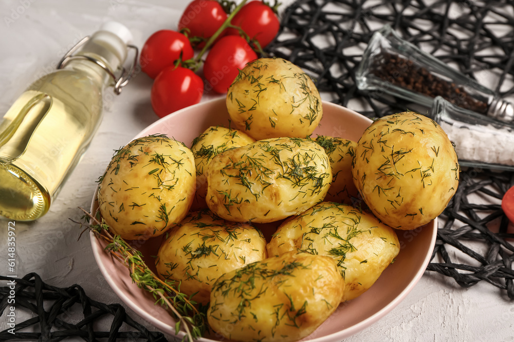 Bowl of boiled baby potatoes with dill and tomatoes on grey background