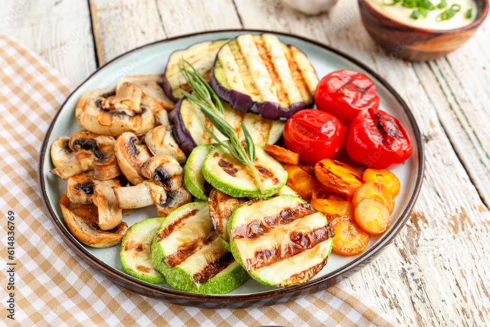 Plate with grilled vegetables and sour cream on white wooden background