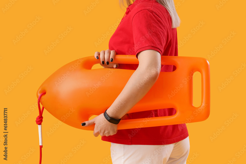 Female lifeguard with rescue buoy on yellow background, closeup