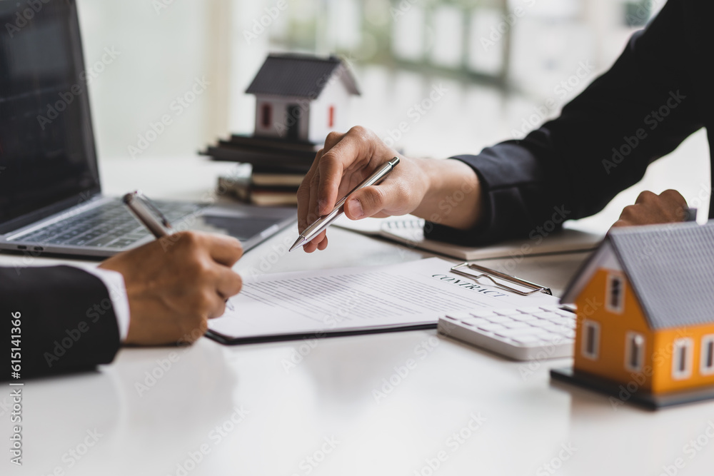 Real estate agent holding pen pointing at contract document for client to sign home purchase agreeme