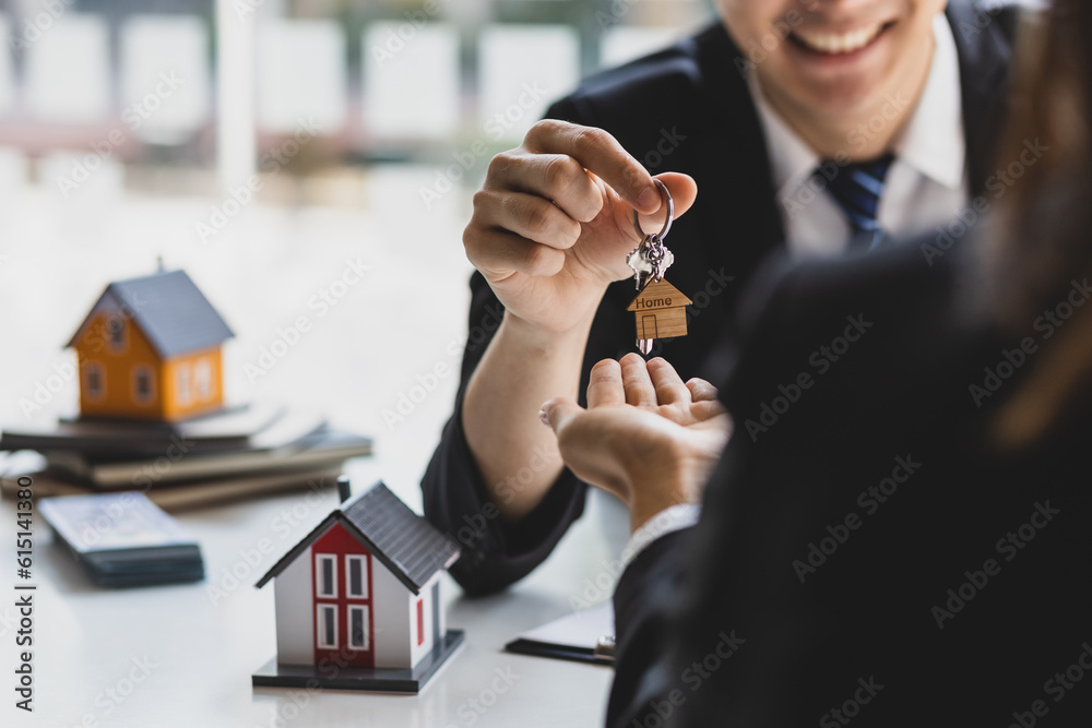 Real estate agent hands over the house keys to a homebuyer after the purchase agreement has been sig