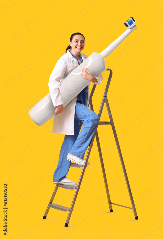 Female dentist with big electric toothbrush on stepladder against yellow background