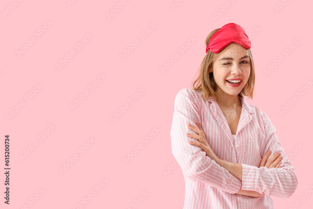 Happy young woman in pajamas on pink background