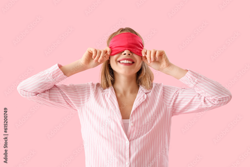 Happy young woman in pajamas on pink background