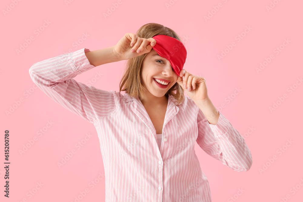 Happy young woman in pajamas on pink background