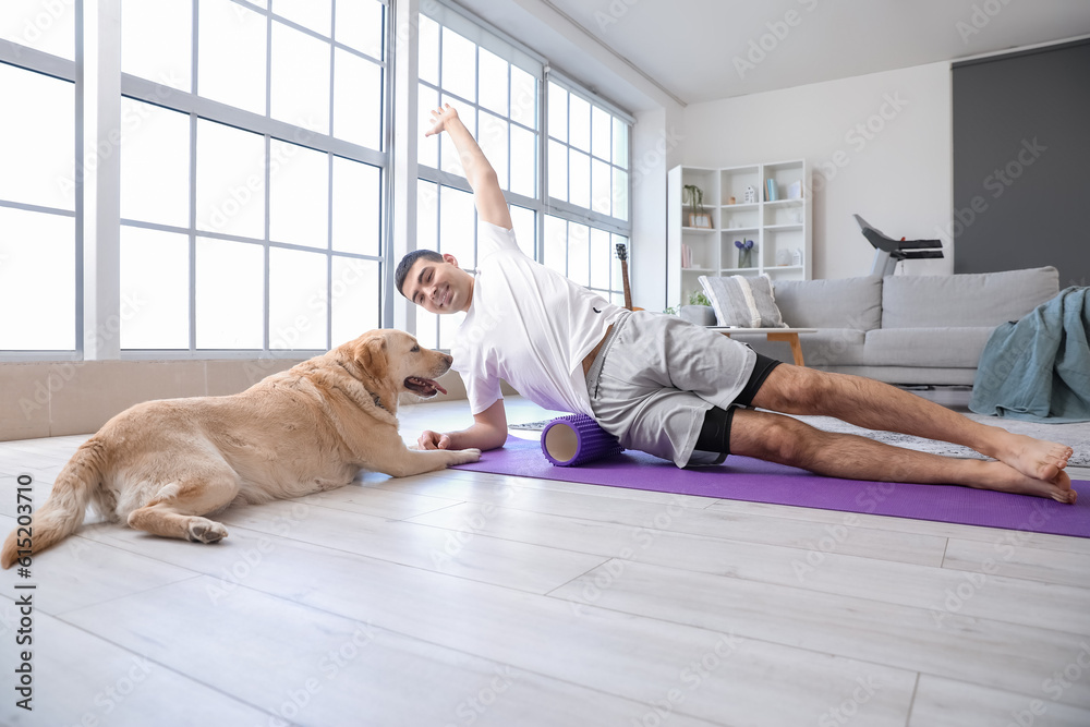 Young man with cute Labrador dog training at home