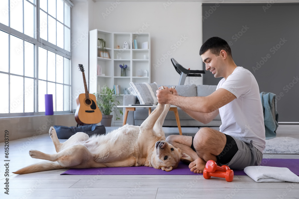 Sporty young man with cute Labrador dog at home