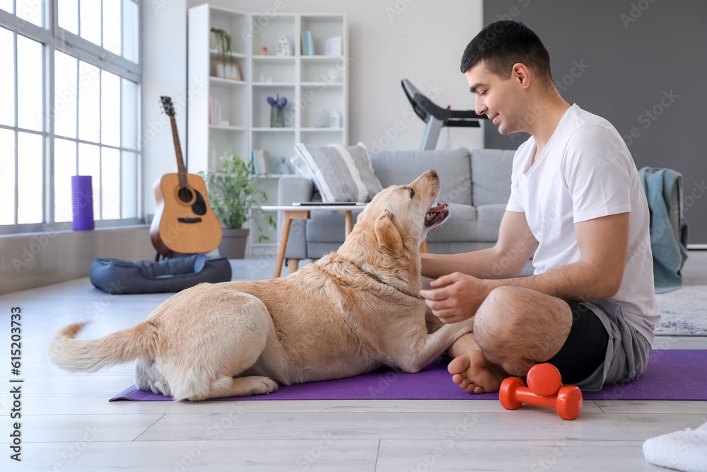 Sporty young man with cute Labrador dog at home