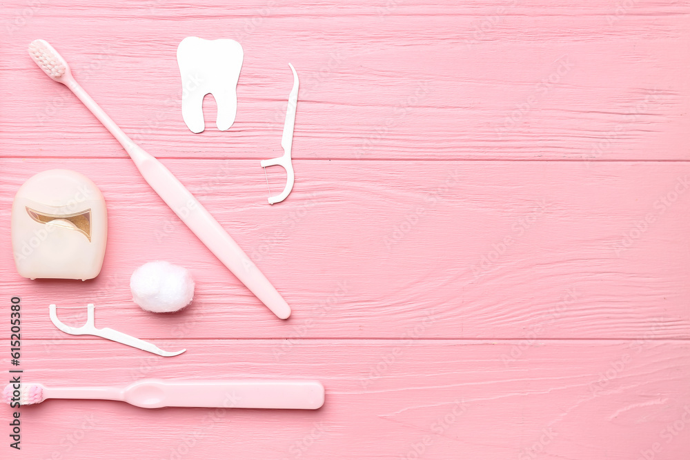 Composition with dental floss, toothpicks and brushes on pink wooden background