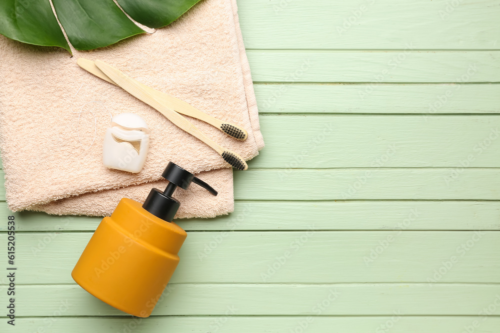 Dental floss and bath accessories on green wooden background