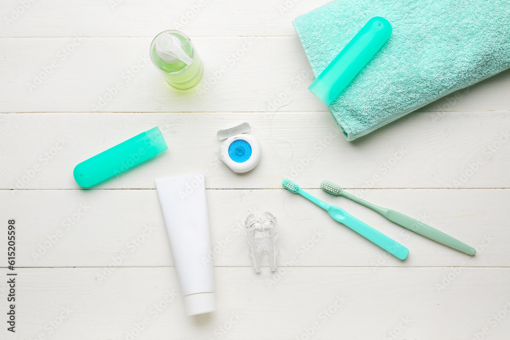 Composition with dental floss, brushes, toothpaste and rinse on white wooden table