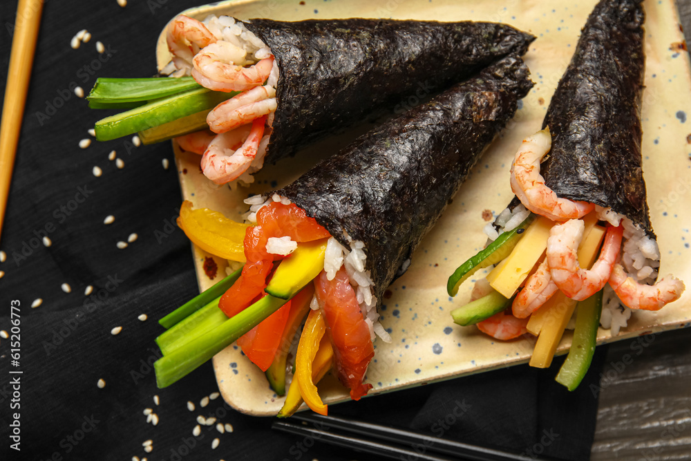 Plate with tasty sushi cones on table, closeup