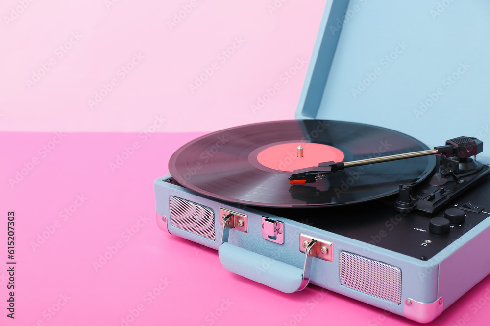 Record player with vinyl disk on table near pink wall, closeup