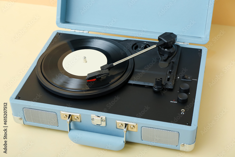 Record player with vinyl disk on table near beige wall