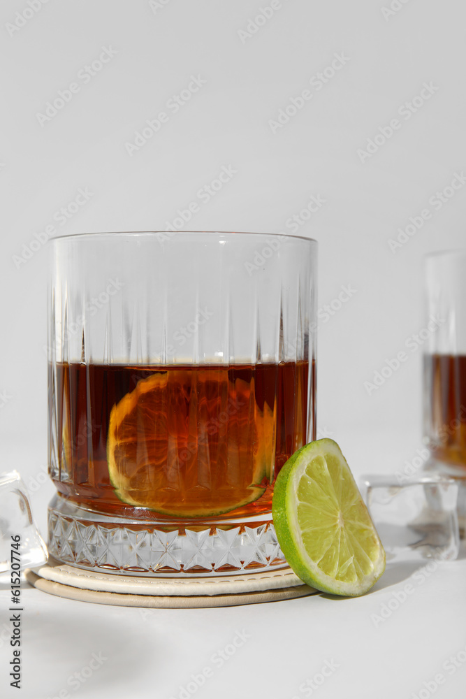 Glass of cold rum with lime on grey background, closeup