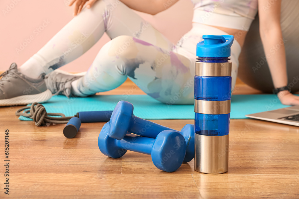 Dumbbells with sports water bottle in gym, closeup