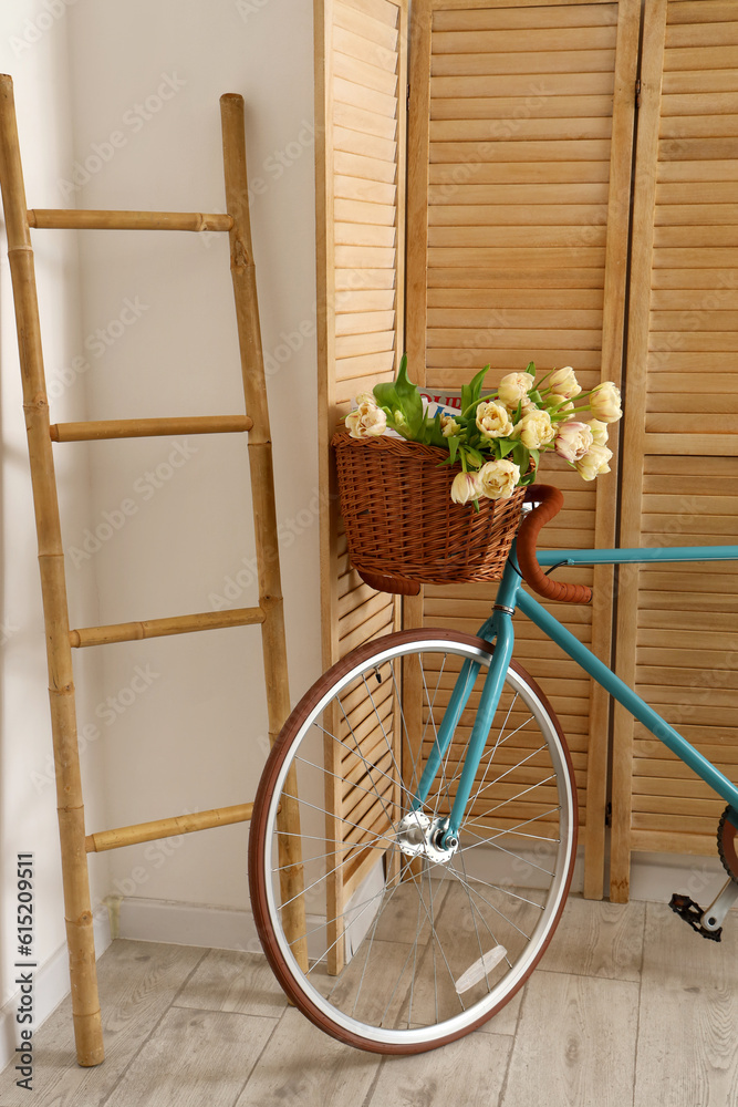 Bicycle with beautiful tulip flowers in interior of living room