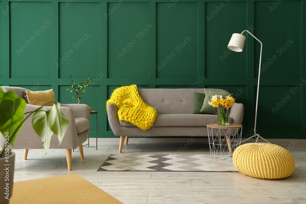 Interior of living room with grey sofa, armchair and narcissus flowers on coffee table