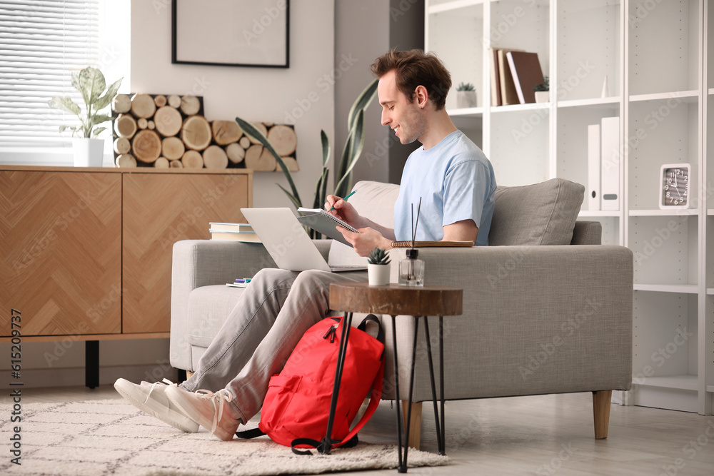 Male student with laptop doing lessons at home