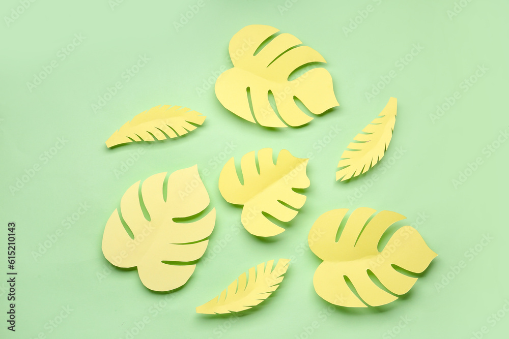 Yellow paper tropical leaves on green background