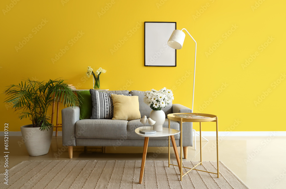 Interior of living room with grey sofa and blooming chrysanthemum flowers on coffee table