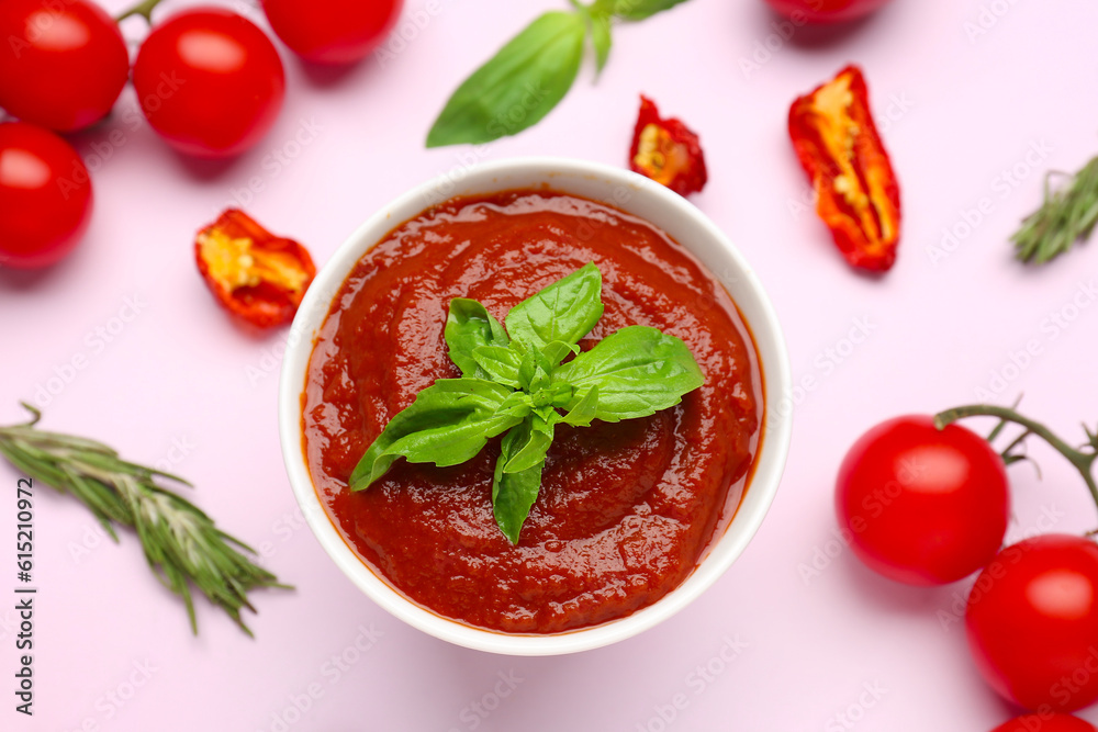 Bowl of delicious tomato sauce and ingredients on lilac background