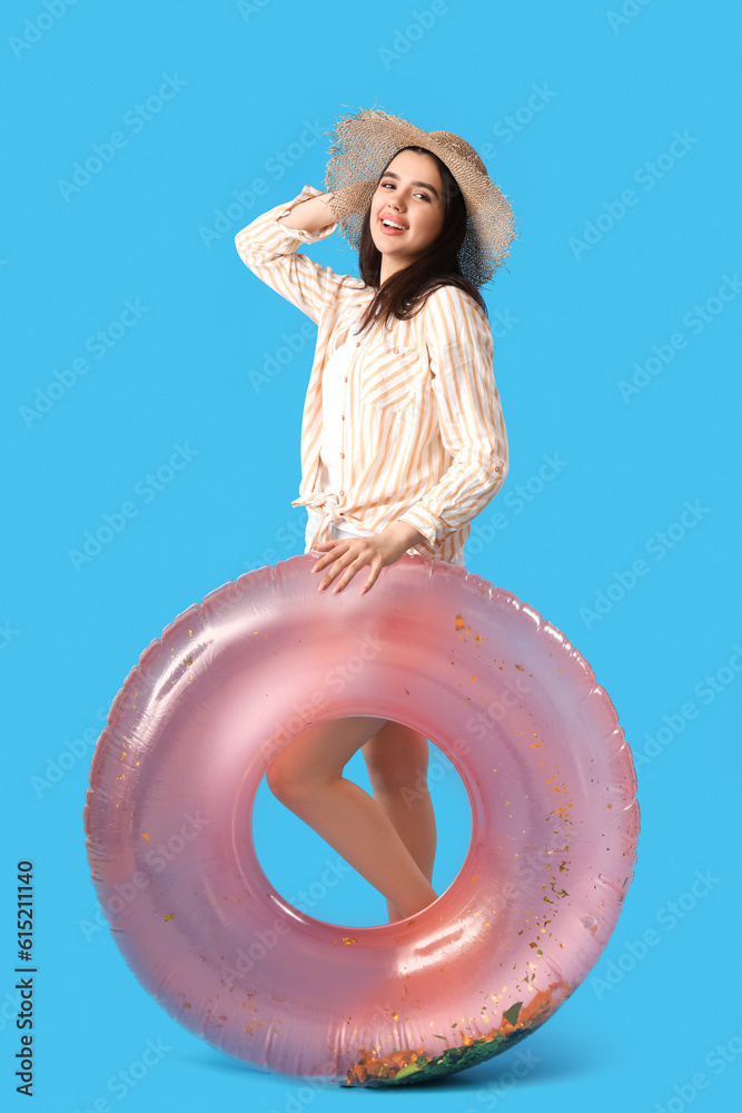 Young woman with pink inflatable ring on blue background