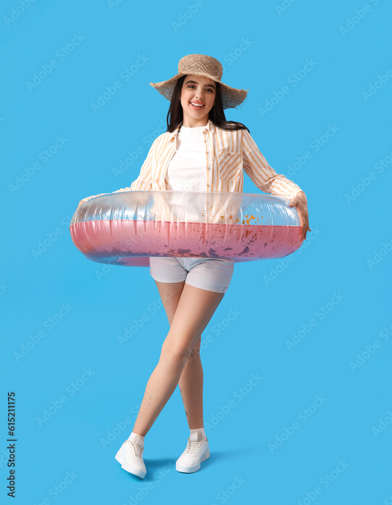 Young woman with pink inflatable ring on blue background