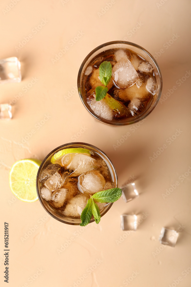 Glasses of cold Cuba Libre cocktail on beige background